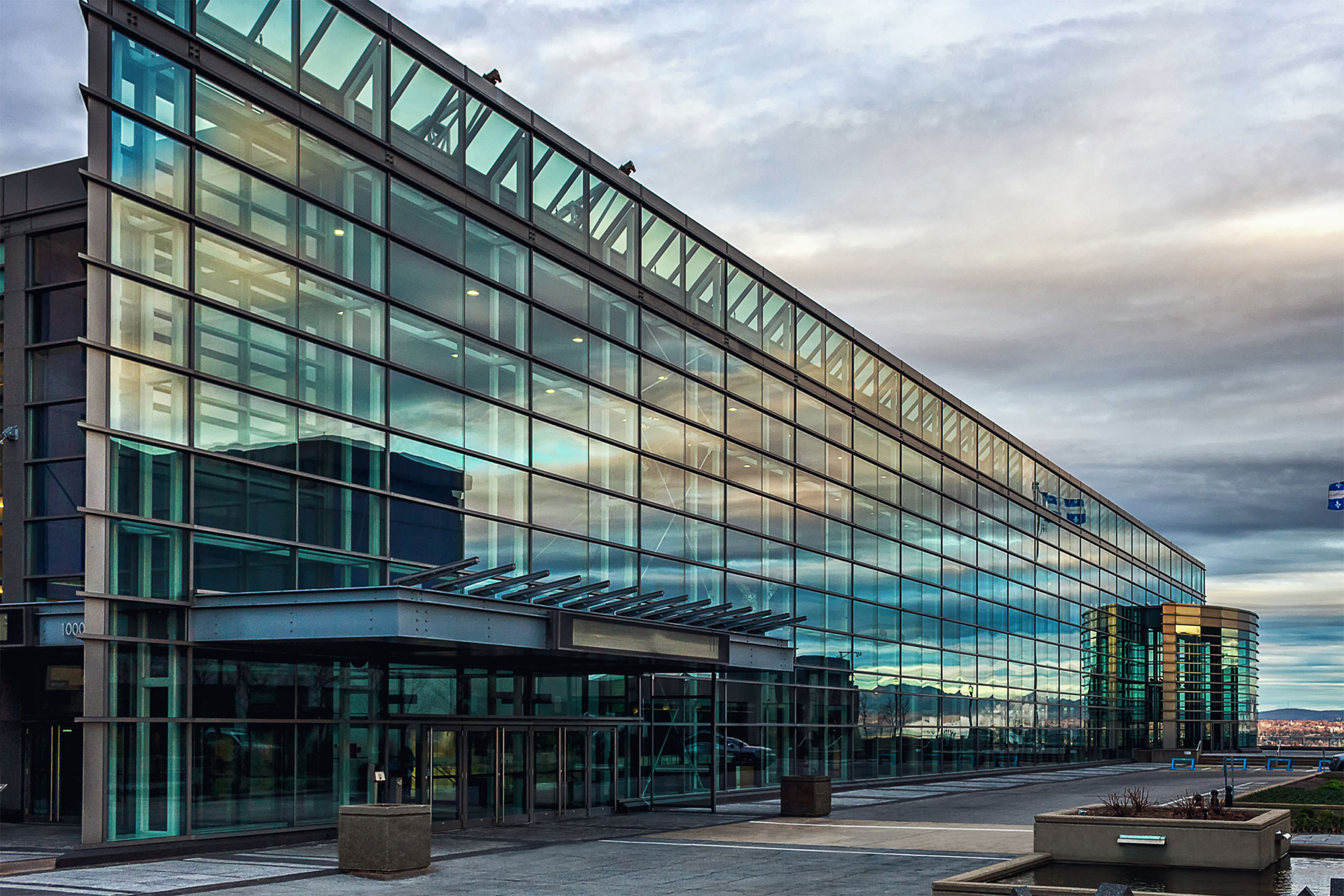 Vue extérieure au crépuscule de la façade vitrée du Centre des congrès de Québec offrant salles et espaces polyvalents pour vos événements.